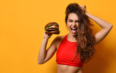 Woman hold big barbecue burger sandwich with hungry mouth happy screaming laughing on yellow...