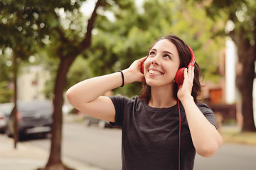 Portrait of young beautiful woman with red headphones listening music