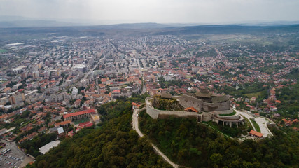 Fototapeta na wymiar Aerial view of Deva Castle with the town in the background on a cloudy sky.