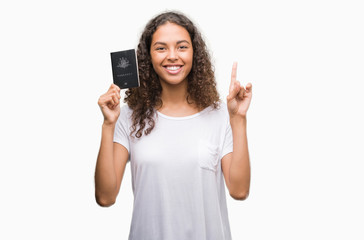 Young hispanic woman holding passport of Australia surprised with an idea or question pointing finger with happy face, number one