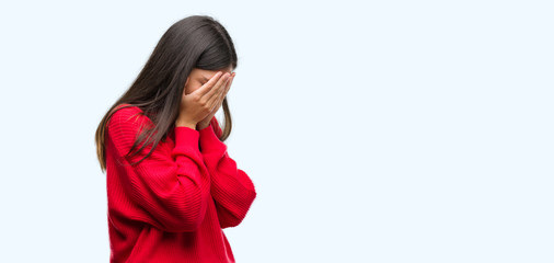 Young beautiful hispanic wearing red sweater with sad expression covering face with hands while crying. Depression concept.