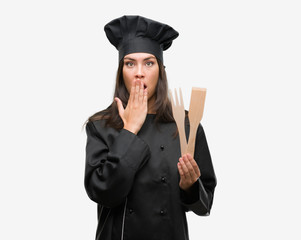 Young hispanic cook woman wearing chef uniform cover mouth with hand shocked with shame for mistake, expression of fear, scared in silence, secret concept