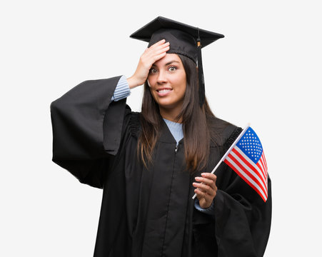 Young hispanic woman wearing graduated uniform holding flag of america stressed with hand on head, shocked with shame and surprise face, angry and frustrated. Fear and upset for mistake.