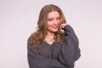 Fototapeta premium Close up portrait of caucasian tender woman with curly hair wearing gray cardigan on white background