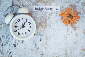 Fall Daylight Saving Time concept with white clock and flowers, flat lay