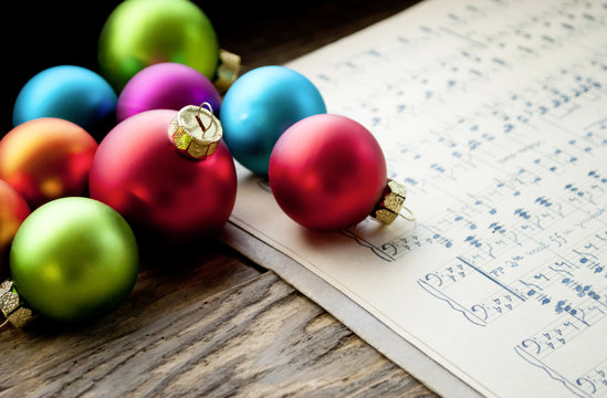 Alte handgeschriebene Musiknoten mit bunten Weihnachtskugeln auf Holz / Treiholz Hintergrund, Weihnachten, xmas 