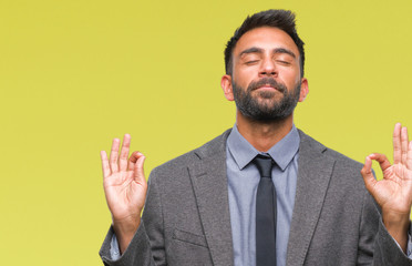 Adult hispanic business man over isolated background relax and smiling with eyes closed doing meditation gesture with fingers. Yoga concept.
