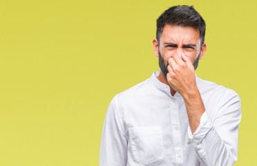 Adult hispanic man over isolated background smelling something stinky and disgusting, intolerable...