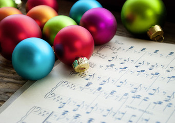 Alte handgeschriebene Musiknoten mit bunten Weihnachtskugeln auf Holz / Treiholz Hintergrund,...