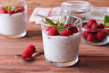 chia pudding in a glass with raspberries on a wood background.