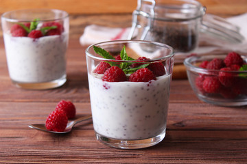 chia pudding in a glass with raspberries on a wood background.