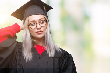 Young blonde woman wearing graduate uniform over isolated background confuse and wonder about...