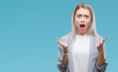Young blonde business woman wearing jacket over isolated background crazy and mad shouting and...