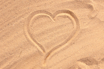 The heart is drawn on the sand. Beach background. Top view