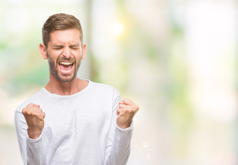 Young handsome man over isolated background very happy and excited doing winner gesture with arms raised, smiling and screaming for success. Celebration concept.