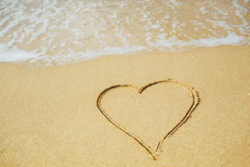 Fototapeta na wymiar Heart shape draw on sandy beach. Love concept