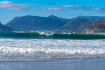Beach and waves across a bay with beautiful mountains in distance.