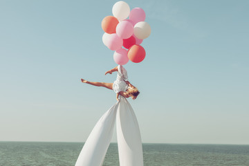 Woman acrobat is spinning in the sky on balloons, she shows the performance.