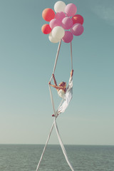 Woman gymnast flies on balls high in the sky and demonstrates twine.