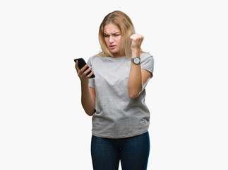 Young caucasian woman sending message using smartphone over isolated background annoyed and frustrated shouting with anger, crazy and yelling with raised hand, anger concept