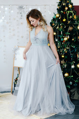 portrait of a woman in a blue dress on a christmas tree background in christmas