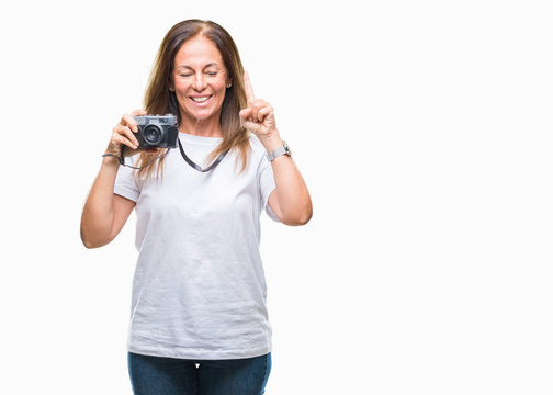 Middle age hispanic woman taking pictures using vintage photo camera over isolated background surprised with an idea or question pointing finger with happy face, number one