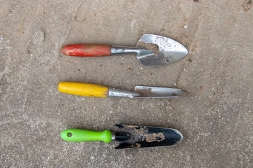 Set of garden tools with colorful handles on cement floor background