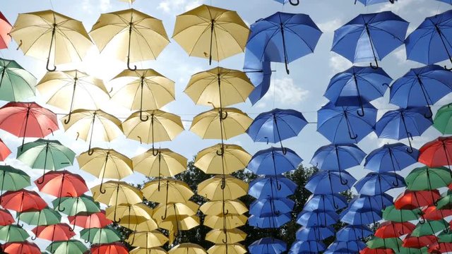 Many colorful parasols in the row. Relaxing scene with umbrellas on the street city. Slider shot

