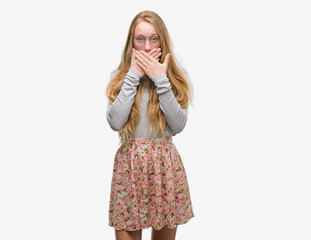 Blonde teenager woman wearing flowers skirt shocked covering mouth with hands for mistake. Secret concept.