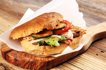 Pulled pork sandwiches with BBQ sauce, cabbage and pickles on wooden table