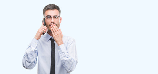 Young business adult man talking on the phone cover mouth with hand shocked with shame for mistake, expression of fear, scared in silence, secret concept