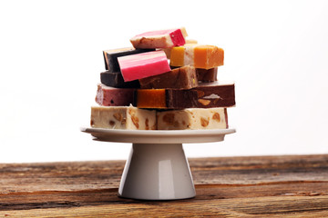 Delicious traditional Italian festive torrone or nougat with nuts on wooden background. Soft nougat blocks with almonds and in diffrent colors. Italian sweets