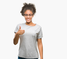 Young afro american woman wearing glasses over isolated background doing happy thumbs up gesture with hand. Approving expression looking at the camera with showing success.