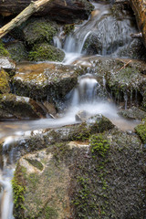 Naklejka na ściany i meble Mountain stream water flow with green moss on wet rocks. River cascade with huge stones.