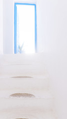 A white stone staircase inside the house with a blue open door.