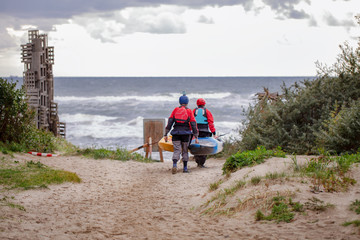 спортсмены несут лодку по песчаному пляжу к морю
