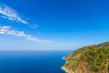 View over the blue Mediterranean Sea and the mountains of Cinque Terre, Italy on a sunny day with blue sky.