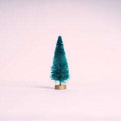 Small artificial Christmas tree on pink pastel background. Minimal style. Christmas and New Year concept.