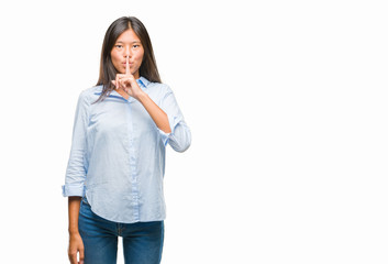 Young asian business woman over isolated background asking to be quiet with finger on lips. Silence and secret concept.
