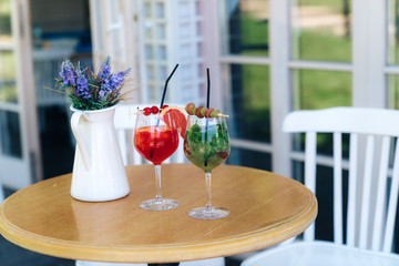 Close-up waiter waits for visitors, prepared for them beautiful fruit and berries decorated with cocktails. I put a decorative vase of flowers on the table, created a cosiness at the table for lovers.