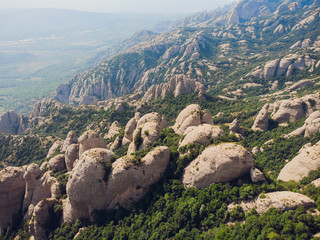 Fototapeta na wymiar Montserrat, Catalonia, Spain. Top View Of Hillside Cave Santa Cova De Montserrat Or Holy Cave Of Montserrat In Summer Day.