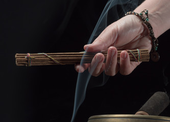 Woman hand with tibetan singing bowl and incense sticks.
