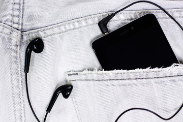Closeup to jeans pocket with smartphone and headphones