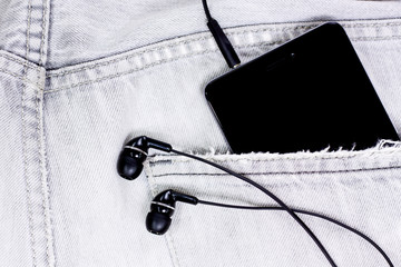 Closeup to jeans pocket with smartphone and headphones