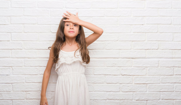 Young hispanic kid over white brick wall surprised with hand on head for mistake, remember error. Forgot, bad memory concept.