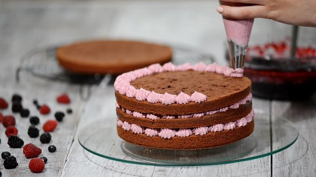 Confectioner is decorating chocolate cake.