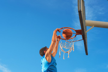 Street basketball athlete performing slam dunk on the court © herraez