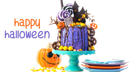 On trend Halloween candyland fantasy novelty drip cake on white background with Happy Halloween text greeting.