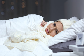 Woman suffering cold in a bed in winter