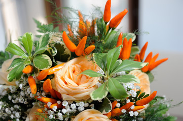 Chilli peppers between orange roses and green leaves